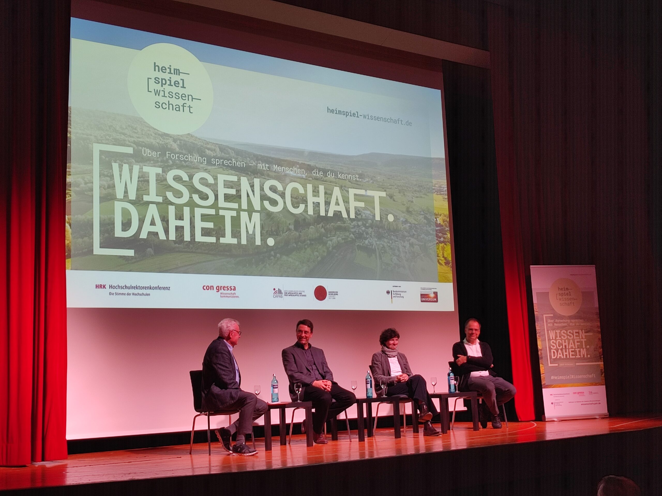 Die drei Professor*innen kommen während der Podiumsdiskussion miteinander ins Gespräch.